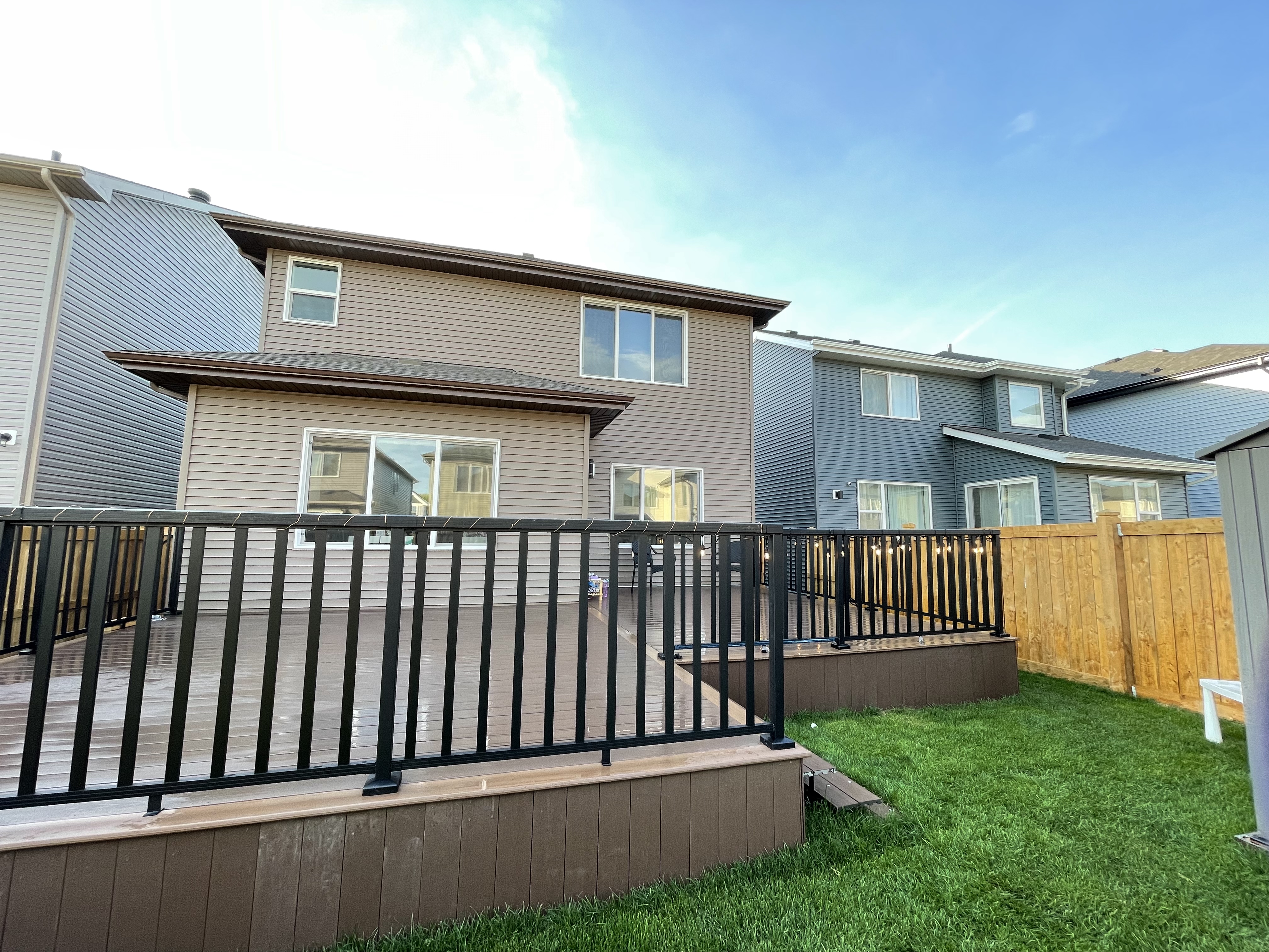 a newly constructed wood deck and iron fence in the backyard