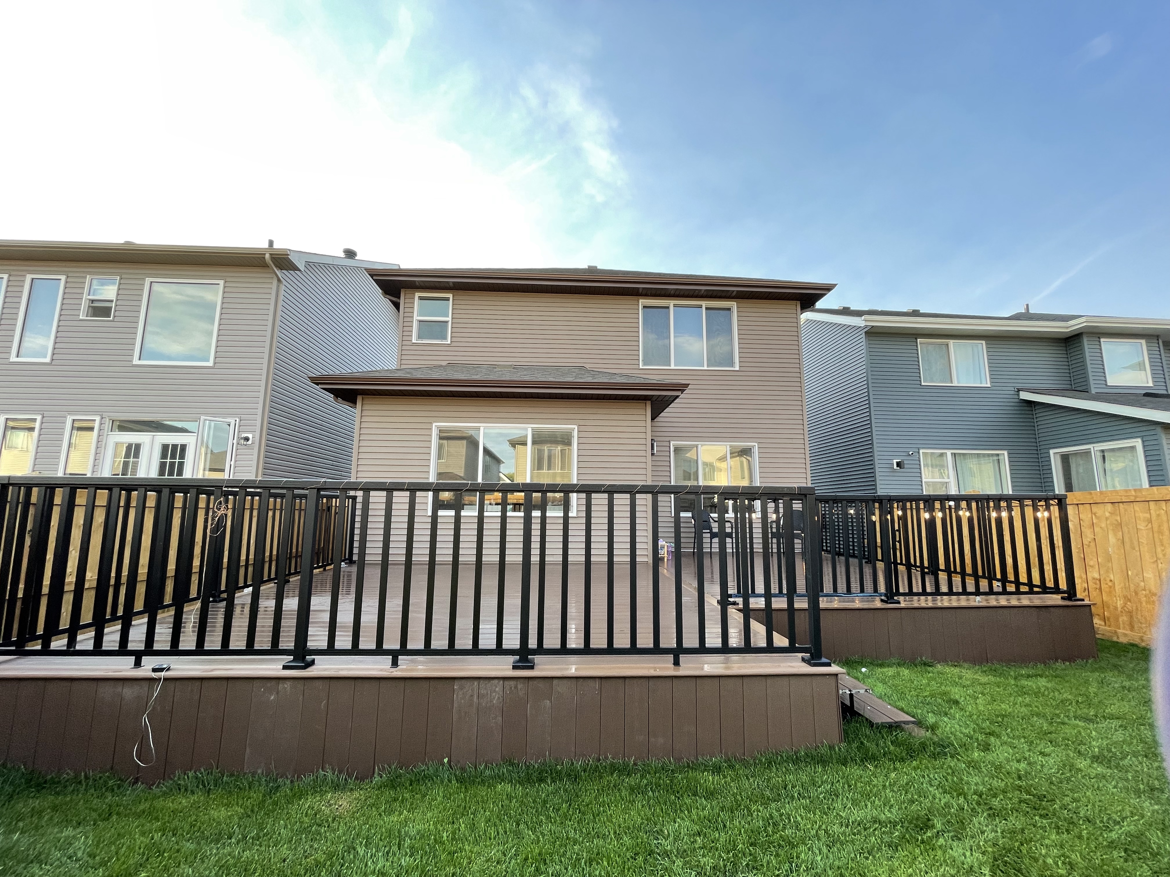 a newly constructed wood deck and iron fence in the backyard